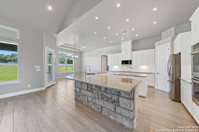 kitchen with light wood finished floors, visible vents, appliances with stainless steel finishes, a large island with sink, and a sink