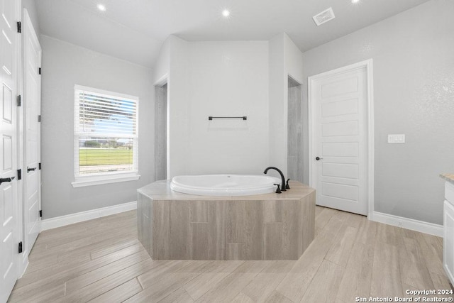 bathroom featuring a garden tub, visible vents, baseboards, and wood finished floors