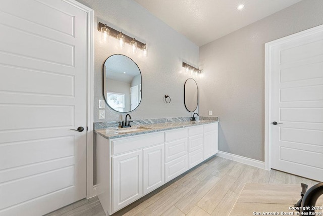 bathroom featuring double vanity, a sink, baseboards, and wood finished floors