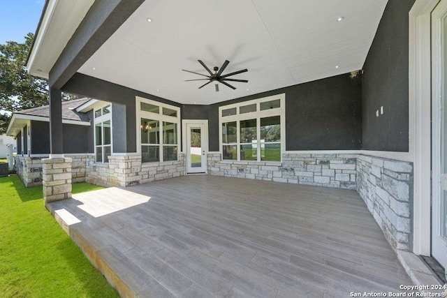 wooden deck featuring ceiling fan and a lawn