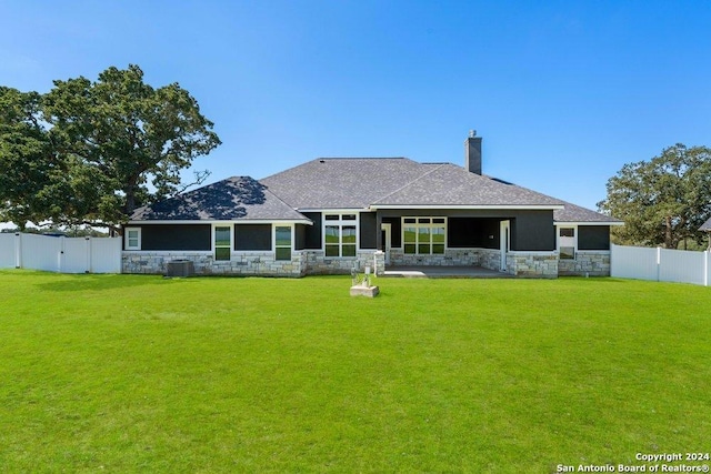 rear view of house with a yard, stone siding, and a fenced backyard