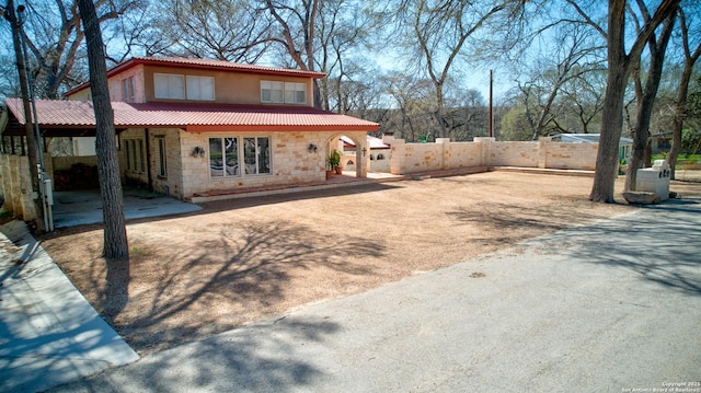 view of front of house featuring a tile roof, fence, stone siding, and stucco siding