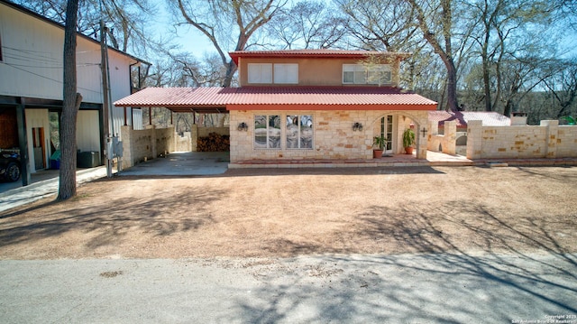 rear view of house featuring stone siding and a tiled roof