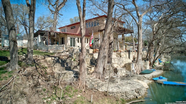 exterior space featuring a patio area, stairs, and a water view