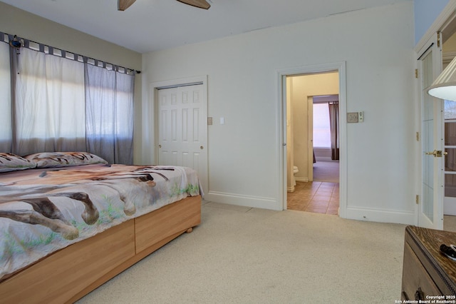 bedroom with a closet, light carpet, baseboards, and connected bathroom