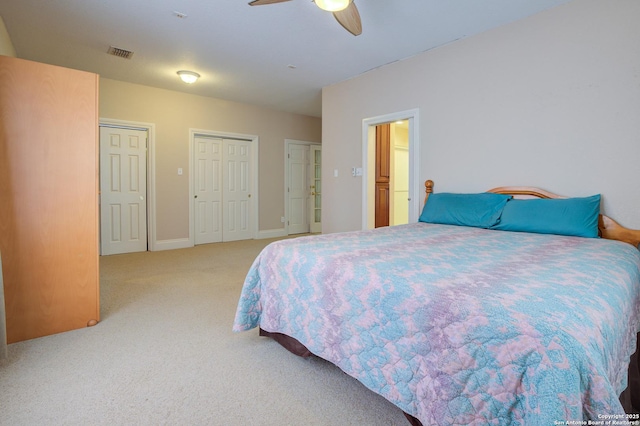 carpeted bedroom with baseboards, a ceiling fan, visible vents, and multiple closets