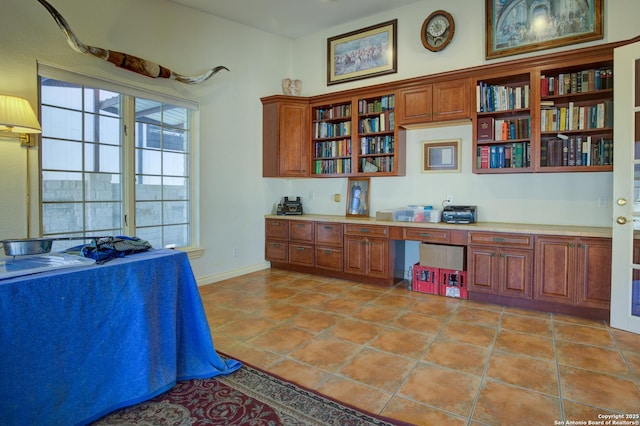 kitchen featuring open shelves, light countertops, brown cabinets, and built in study area