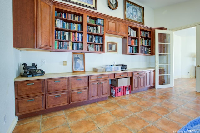 office area with light tile patterned floors, baseboards, built in desk, and french doors