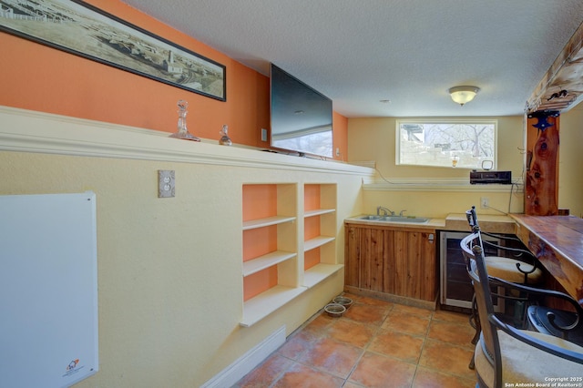 kitchen with a sink, a textured ceiling, and light tile patterned floors