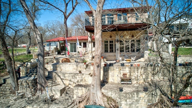 rear view of house featuring stairway, a patio, a balcony, and a fire pit