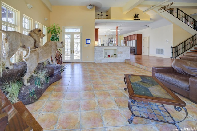 living room with stairway, light tile patterned floors, visible vents, high vaulted ceiling, and beamed ceiling