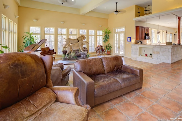 living area with beamed ceiling, light tile patterned flooring, and a towering ceiling