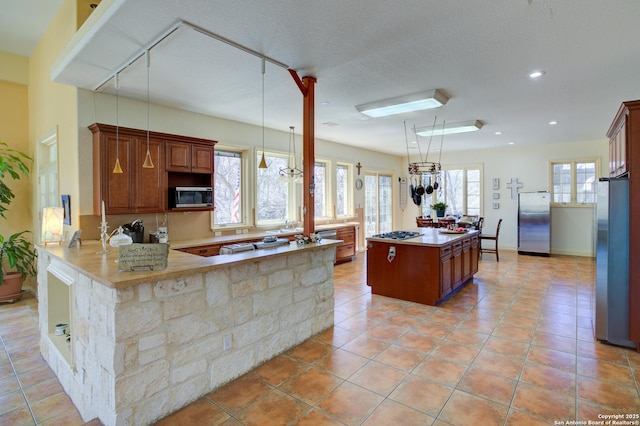 kitchen featuring plenty of natural light, a kitchen island, appliances with stainless steel finishes, and a peninsula