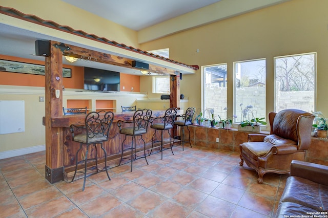 bar featuring tile patterned flooring, bar, and baseboards