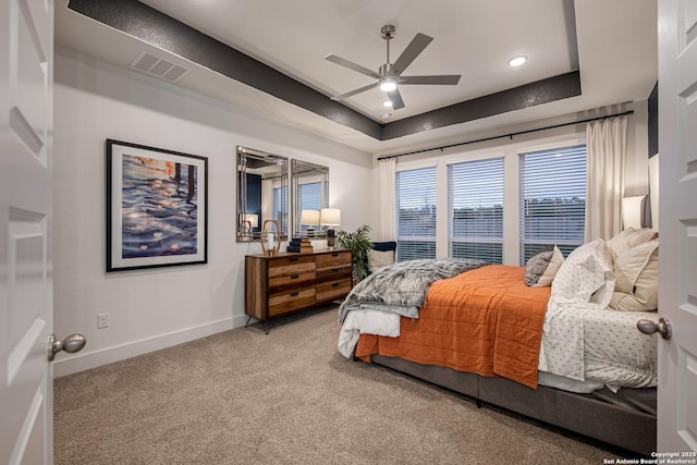 bedroom with a raised ceiling, visible vents, baseboards, and carpet flooring