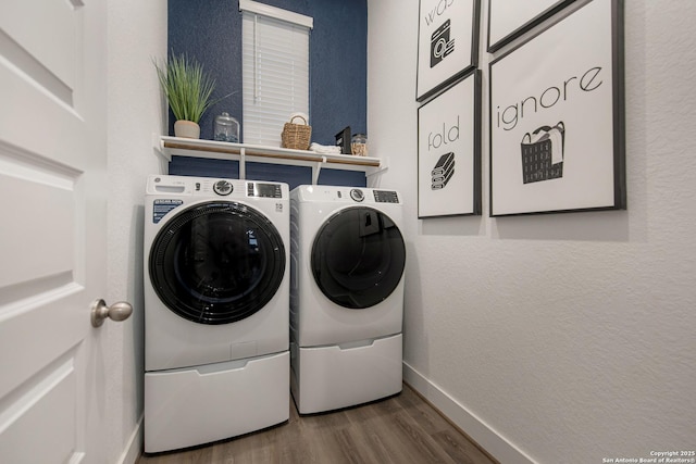 laundry area featuring a textured wall, washing machine and dryer, wood finished floors, laundry area, and baseboards