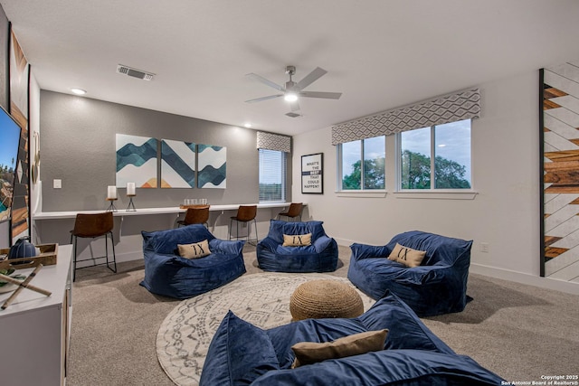 carpeted living area with baseboards, visible vents, and ceiling fan