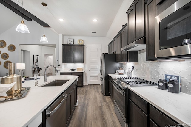 kitchen featuring under cabinet range hood, stainless steel appliances, a sink, dark wood-style floors, and tasteful backsplash