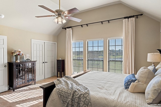 bedroom with a ceiling fan, a closet, vaulted ceiling, and light tile patterned floors