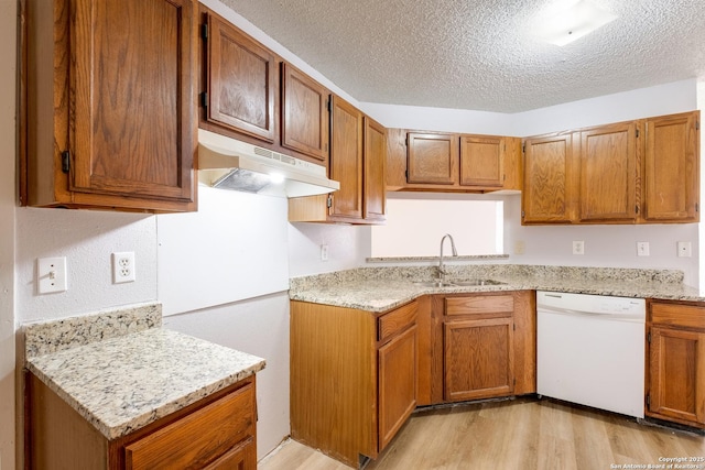 kitchen with brown cabinets, light wood-style flooring, a sink, dishwasher, and under cabinet range hood