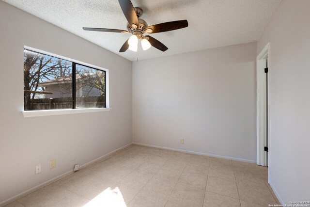 unfurnished room featuring a textured ceiling, light tile patterned flooring, a ceiling fan, and baseboards