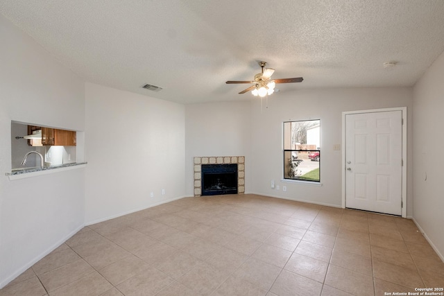 unfurnished living room featuring a fireplace, lofted ceiling, visible vents, a sink, and ceiling fan