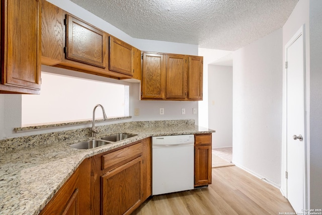 kitchen with brown cabinetry, white dishwasher, a textured ceiling, a sink, and light wood-type flooring