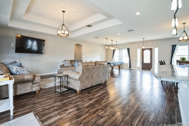 living area featuring visible vents, a raised ceiling, and dark wood-type flooring