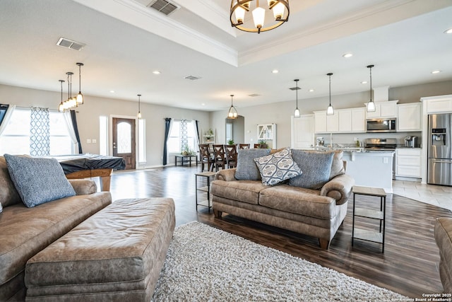 living room with ornamental molding, a tray ceiling, visible vents, and recessed lighting