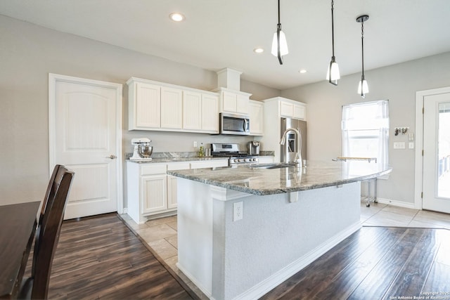 kitchen with light wood-style flooring, a center island with sink, appliances with stainless steel finishes, and a sink