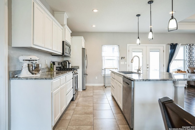 kitchen featuring french doors, a center island with sink, stainless steel appliances, white cabinets, and a sink