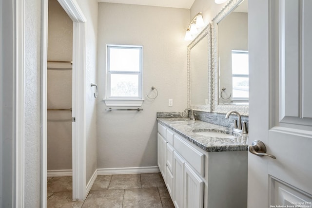 bathroom with double vanity, plenty of natural light, baseboards, and a sink