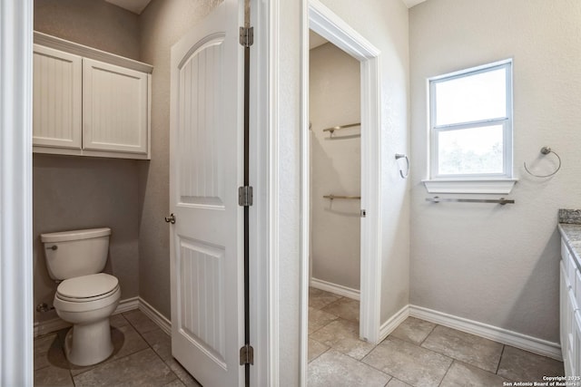 bathroom with toilet, tile patterned flooring, vanity, and baseboards