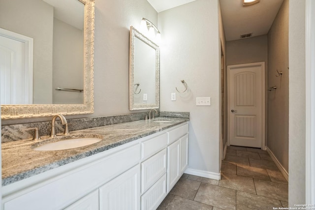 bathroom featuring double vanity, a sink, visible vents, and baseboards