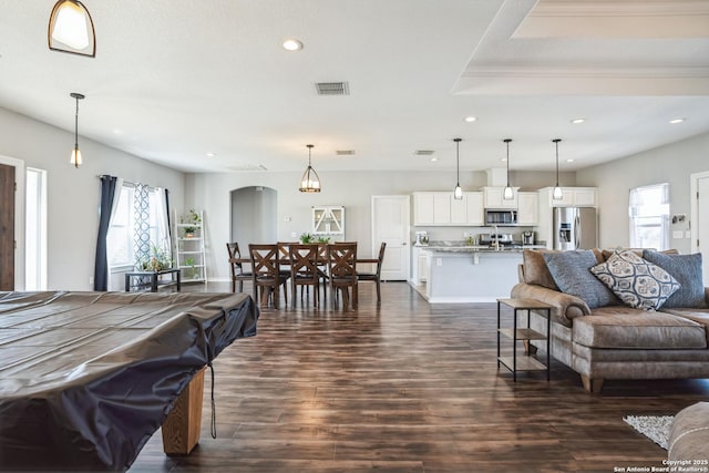 living area with visible vents, arched walkways, dark wood-type flooring, and recessed lighting