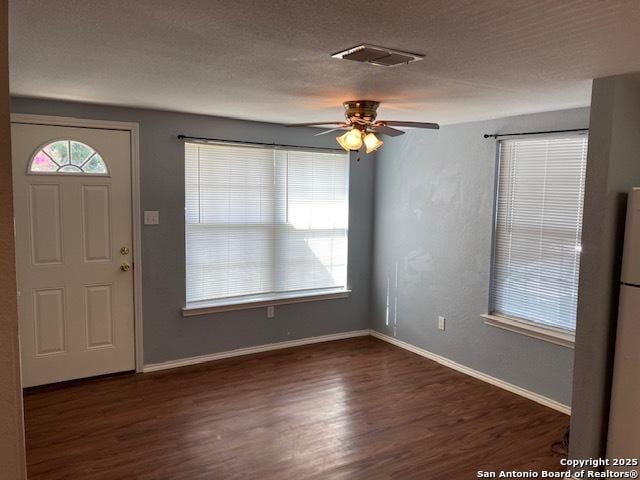 entrance foyer featuring visible vents, a textured ceiling, baseboards, and wood finished floors