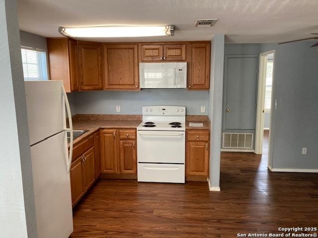 kitchen with dark wood-style floors, light countertops, white appliances, and visible vents