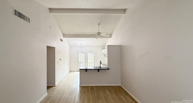 corridor featuring vaulted ceiling with beams, visible vents, a textured ceiling, wood finished floors, and baseboards