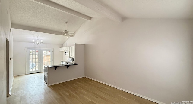 interior space featuring french doors, vaulted ceiling with beams, a textured ceiling, wood finished floors, and baseboards