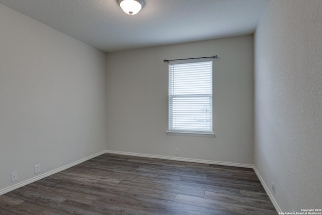 unfurnished room featuring baseboards and dark wood-style floors