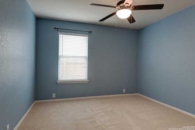 carpeted empty room with baseboards, ceiling fan, and a textured wall