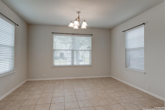 empty room with a notable chandelier and baseboards