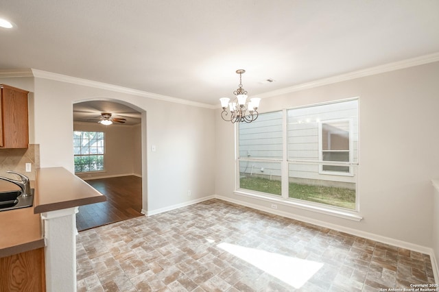 unfurnished dining area featuring ornamental molding, arched walkways, a sink, and baseboards