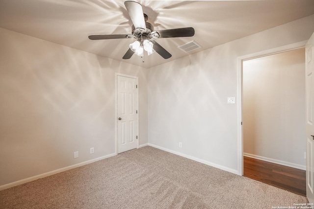 carpeted spare room with a ceiling fan, visible vents, and baseboards