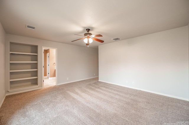 spare room featuring built in shelves, visible vents, carpet floors, and baseboards