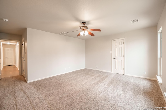 carpeted spare room featuring ceiling fan, visible vents, and baseboards