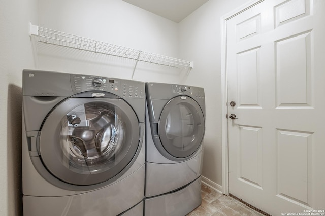 washroom featuring laundry area, baseboards, and washing machine and clothes dryer