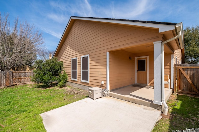 rear view of property with fence, a lawn, and a patio