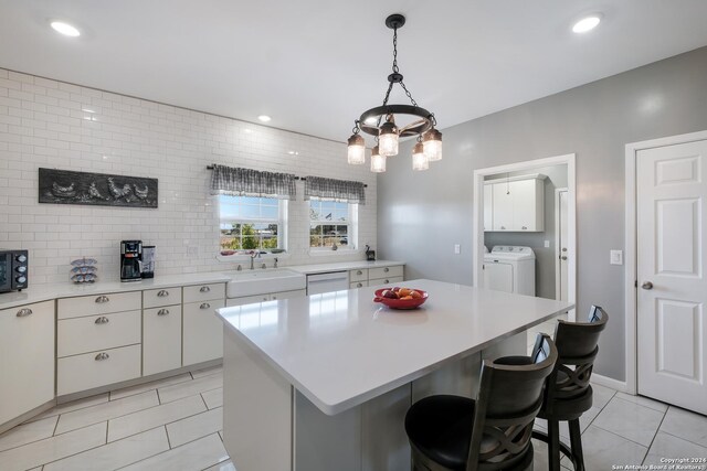 kitchen with tasteful backsplash, dishwasher, a kitchen breakfast bar, light countertops, and white cabinetry