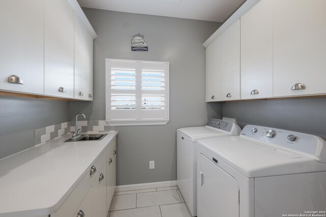 clothes washing area with light tile patterned floors, a sink, baseboards, cabinet space, and washer and clothes dryer